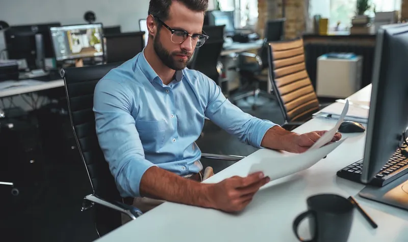 Editor reviewing a printed press release at his desk